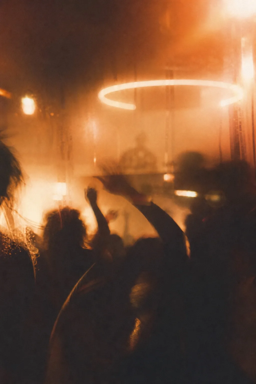 Festival silhouettes beneath blurred amber lights